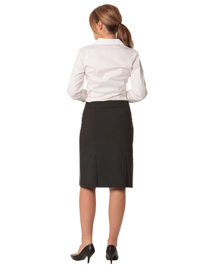 A black wool stretch pleated skirt, seen from the back, paired with a white shirt and heeled shoes.