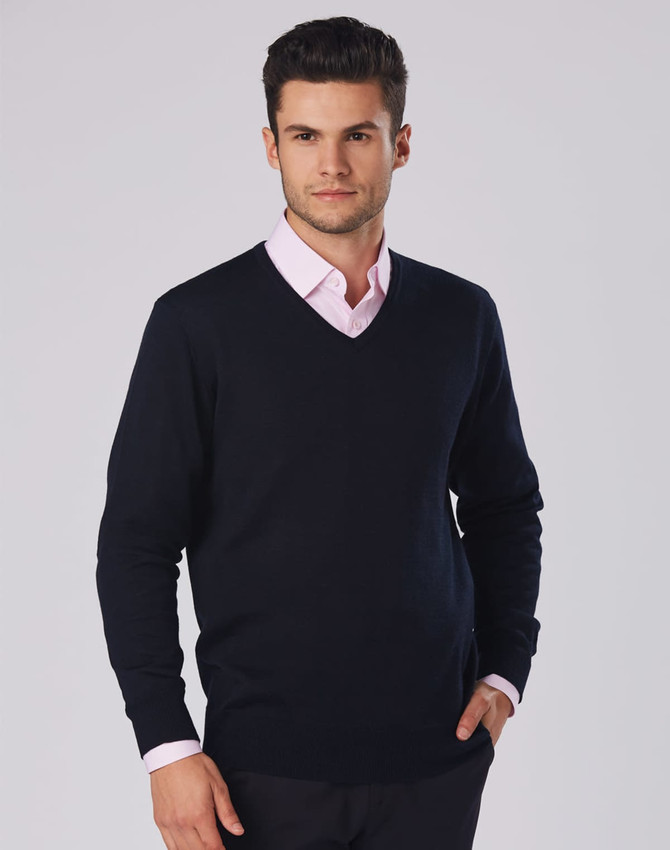 A men's 100% Merino wool V-neck long-sleeve sweater in navy, featuring a fitted design and worn over a light pink shirt.