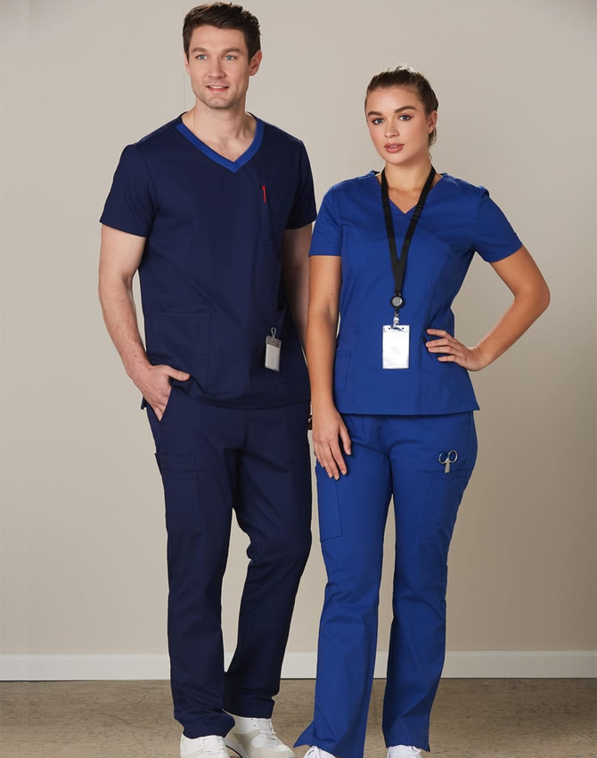 A man and woman wear solid colour scrub tops and pants in navy and blue, with badges and a logo present.