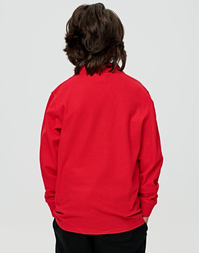 A red long sleeve polo shirt for kids, featuring a simple design and a logo on the back.