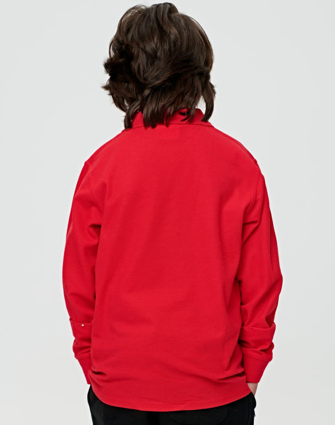 A red long sleeve polo shirt for kids, featuring a collar and a plain back design. The shirt has a logo.