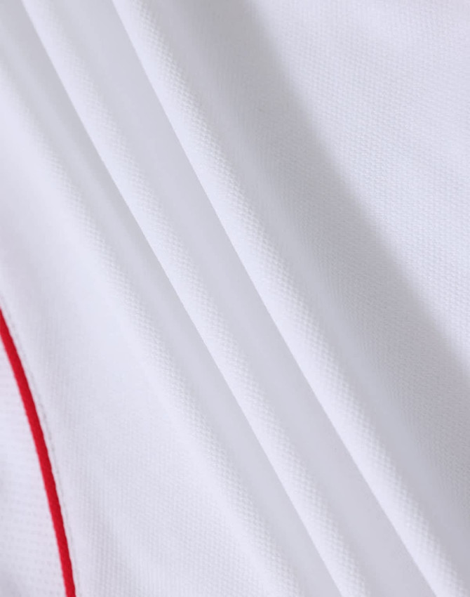 A white polo shirt featuring subtle red detailing and a textured fabric. It includes a logo.