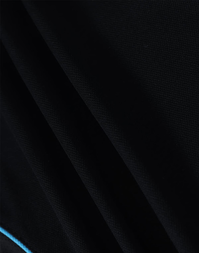 A close-up of a black polo shirt with a textured fabric and a blue accent detail.