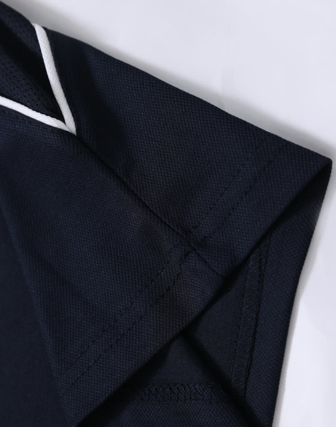 A navy blue kids' polo shirt with a white trim on the collar and sleeve. It features a logo on the chest.