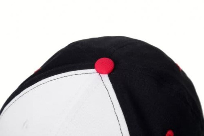 A black and white sport cap with red accent buttons on top. The cap features a logo or branding detail.