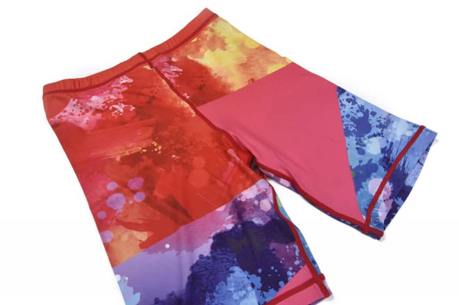 A pair of women's long shorts in vibrant shades of red, pink, and blue with abstract patterns.