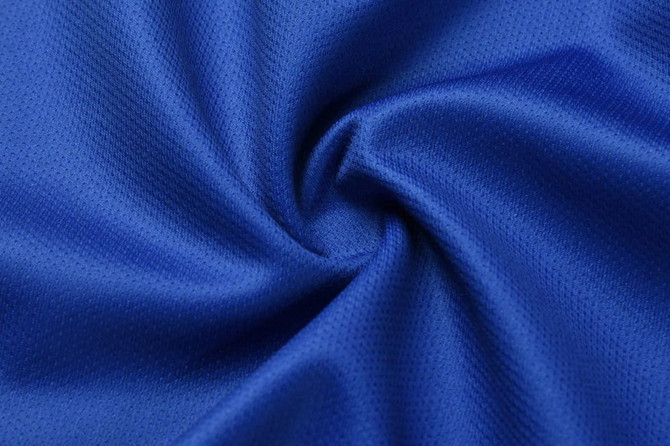 A close-up view of blue training shorts fabric, featuring a smooth and breathable texture with a logo present.