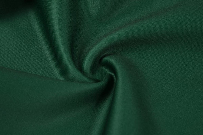 A close-up of green fabric, showcasing a smooth texture with a slight sheen and a swirl pattern.