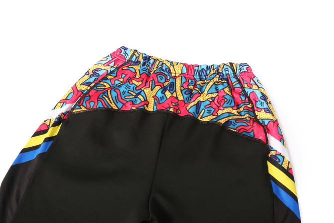WARM UP PANTS in black with a colourful graphic pattern on the waistband and side panels, featuring a logo.