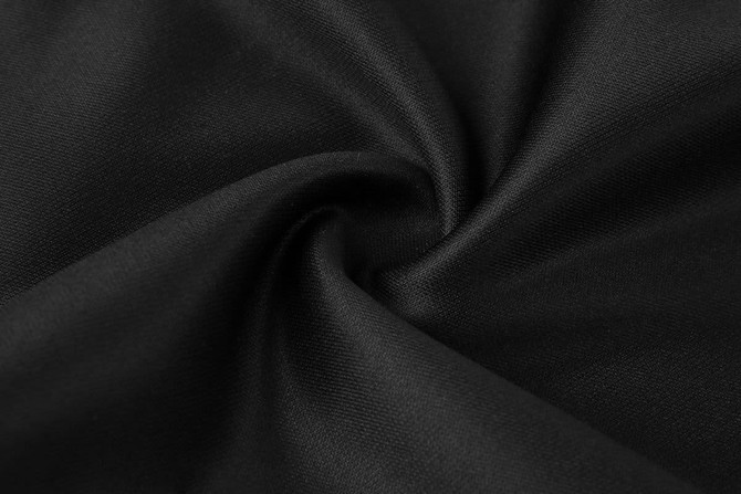 A close-up of black training pants fabric, showcasing a smooth, woven texture. The image features a subtle swirl pattern.