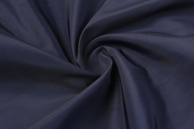 A close-up of navy fabric, featuring a smooth texture with a twisted pattern. The image includes branding elements.