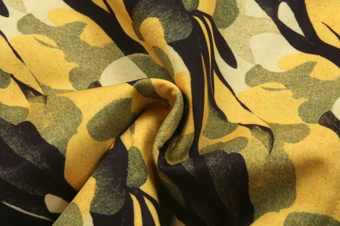 A close-up of fabric featuring a yellow and black camouflage pattern with natural motifs.