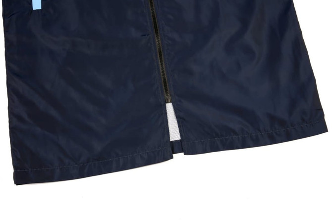 A navy blue sublimation coat featuring a zip closure and a mesh lining detail. The design includes a branding logo.