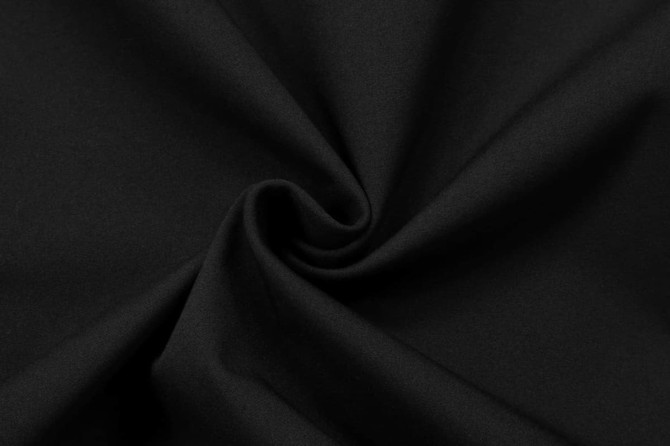 A black softshell fabric with a smooth, folded texture, featuring a logo.