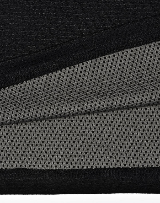 A close-up of a black polo shirt featuring a breathable grey mesh fabric beneath. The shirt includes a logo.