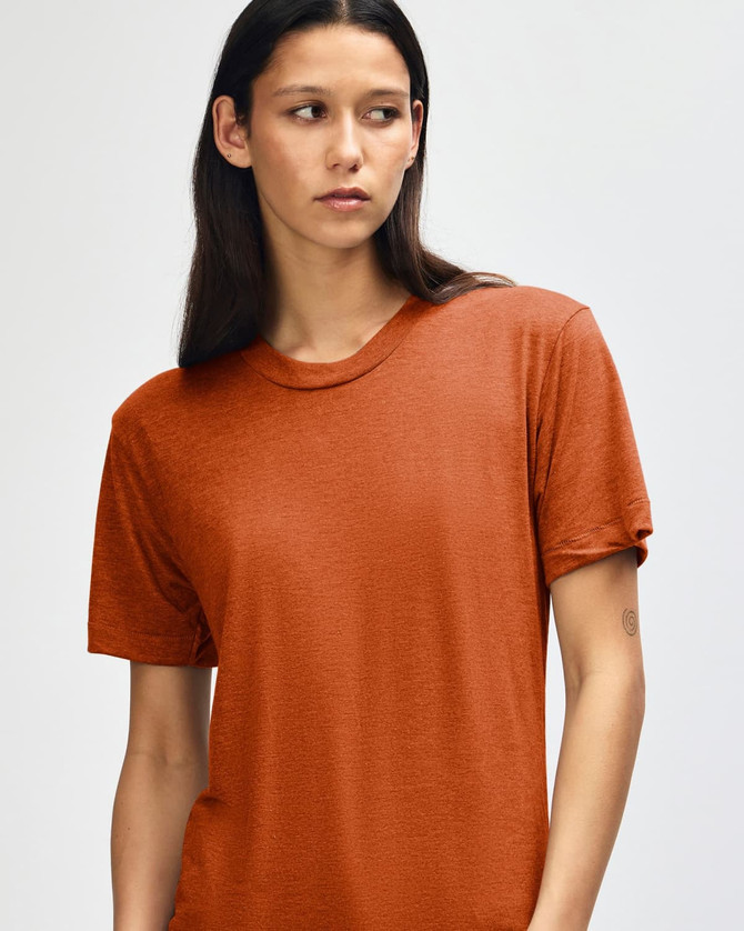 A model wears an orange American Apparel Tri-Blend T-Shirt, featuring a relaxed fit and a subtle texture.
