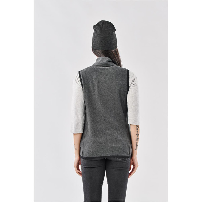 A dark grey beanie worn by a person with long hair, standing in a grey outfit, viewed from the back.