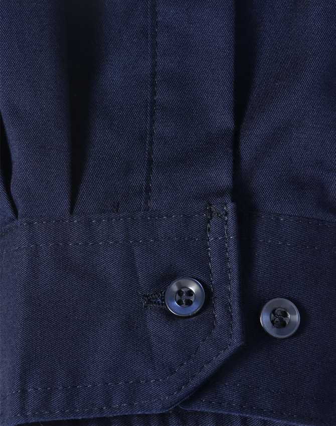 A close-up of a blue long-sleeve shirt featuring segmented tape, with a buttoned cuff detail.