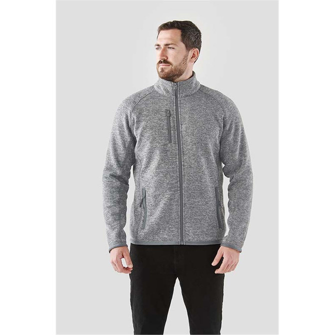 A grey full zip fleece jacket featuring a collar and zippered pockets, worn by a man standing against a plain background.