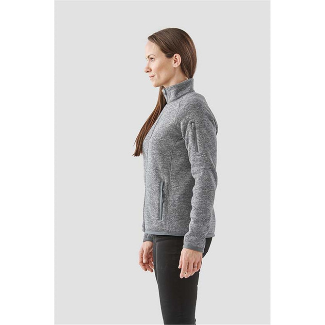A grey women's fleece jacket with a full zip, featuring side pockets and a high collar. It has a logo on it.