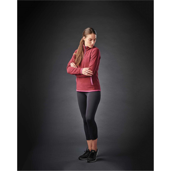 A female model wearing a maroon women's fleece 1/4 zip jumper paired with black leggings and athletic shoes.