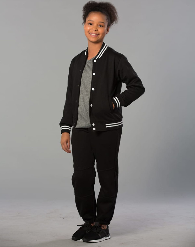 A girl is wearing black fleecy track pants with zips, cuffs, and knee padding, paired with a grey T-shirt and black jacket.