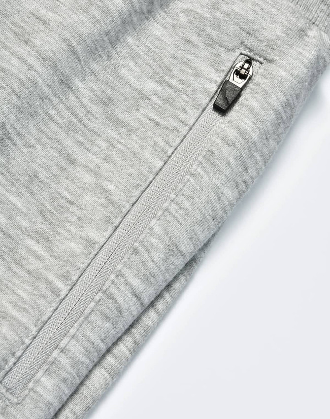 A close-up of grey kids' poly/cotton terry sweat pants featuring a zip pocket and soft fabric texture.