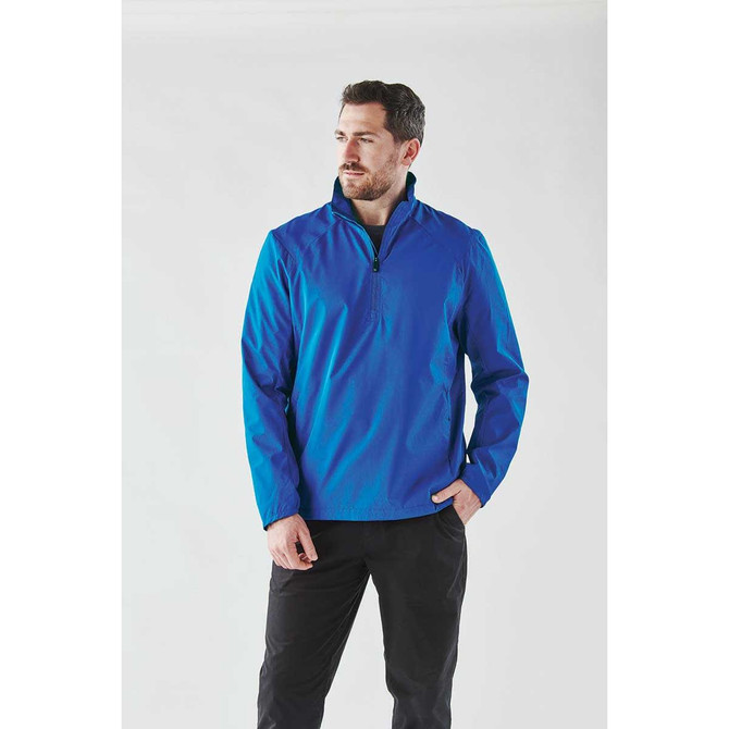 A man wearing a bright blue 1/4 zip anorak jacket, displayed against a plain background. The jacket features a logo.