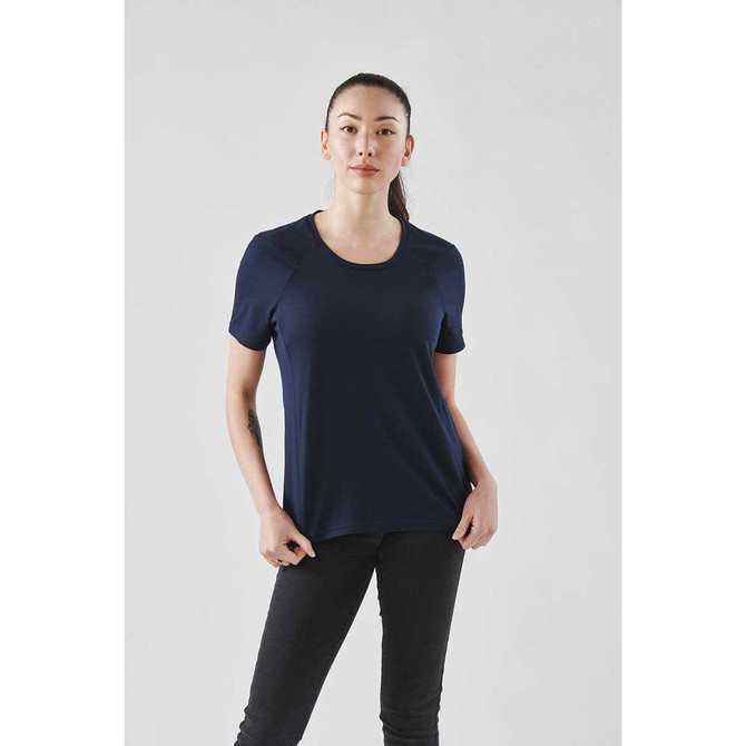 A woman models a navy blue short sleeve tee, featuring a smooth fabric and a simple design. The shirt has a logo.
