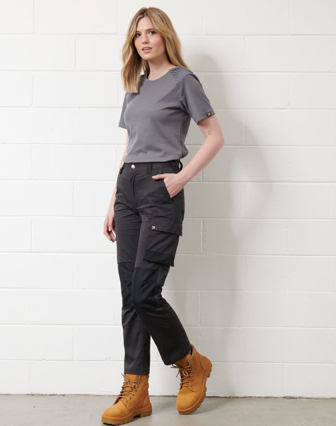 A woman in a grey short-sleeve T-shirt poses with black cargo pants and tan boots, featuring a logo.