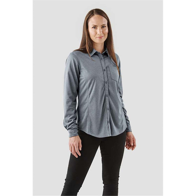 A woman wearing a grey long sleeve button-up shirt with a chest pocket and a logo.
