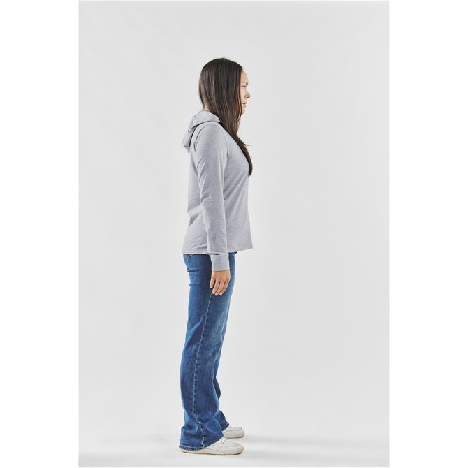 A side view of a woman wearing a grey hoodie with a hood, paired with blue jeans. The hoodie has a logo.