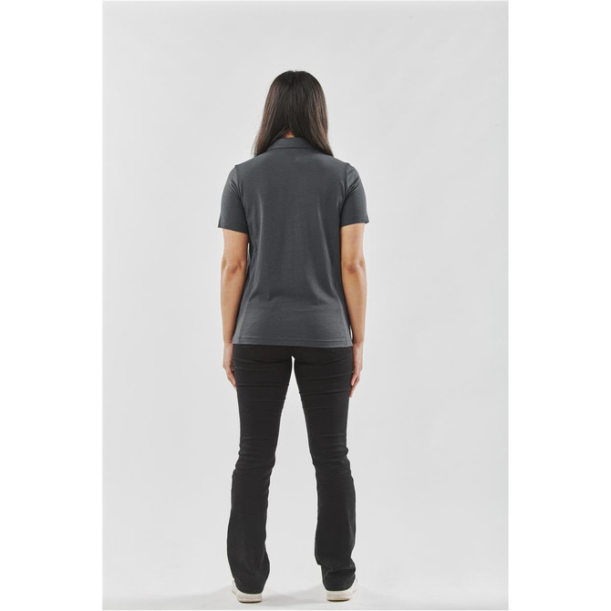 A woman stands with her back to the camera, wearing a dark grey women's polo shirt paired with black pants.