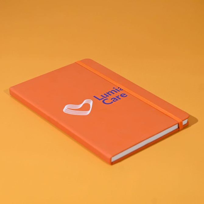 An orange A5 notebook with a logo on the cover and an elastic band closure.