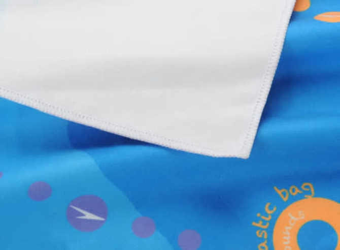 A beach towel featuring a double-faced pile, with vibrant blue and white colours and abstract designs.