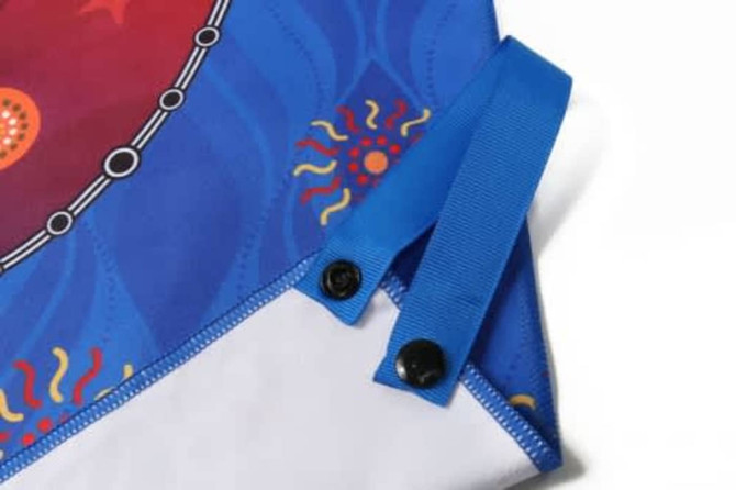 A blue-handled hand towel featuring a colourful, patterned design with snaps at the top for secure hanging.