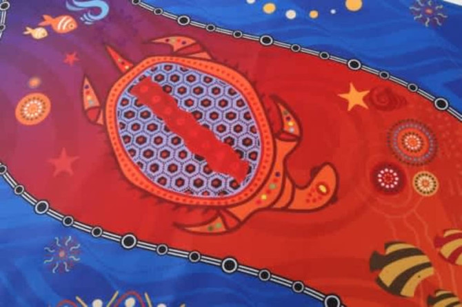 A colourful hand towel featuring intricate patterns of a turtle, starfish, and abstract designs in red and blue.