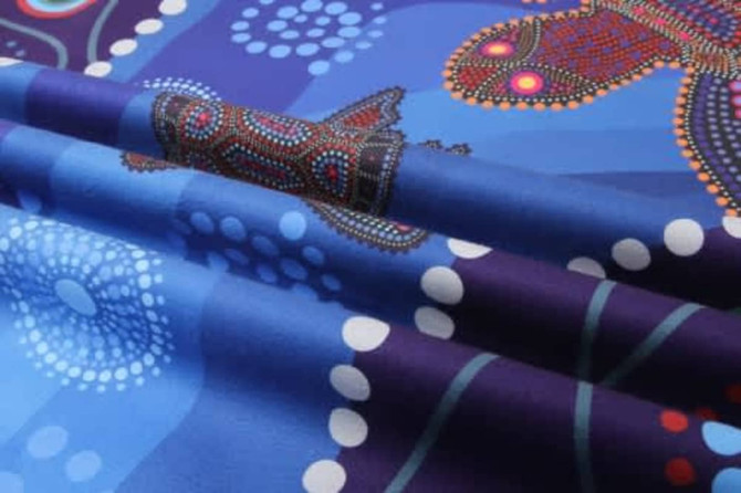 A vibrant spread towel featuring intricate patterns in shades of blue, purple, and red with decorative elements.