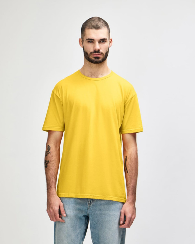 A yellow Gildan Softstyle adult t-shirt displayed on a model, featuring a logo on the shirt.