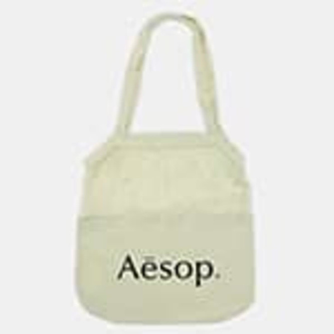 A light cream cotton shopping tote with a logo on the front and two handles.