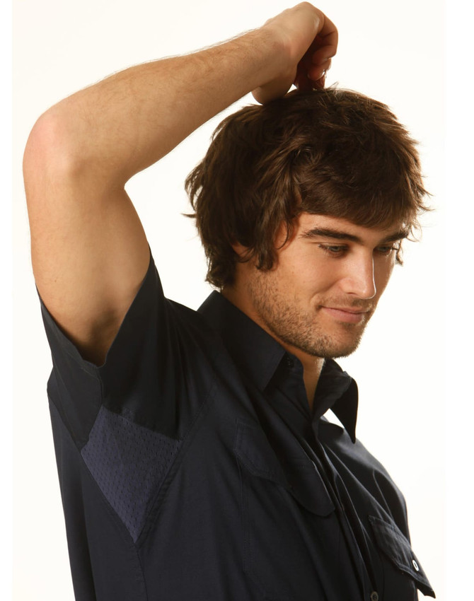 A dark blue short-sleeved cotton work shirt displayed on a young man with tousled hair, featuring a logo on the chest.