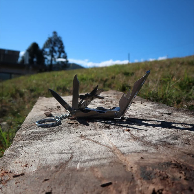 A multi-tool with various tools displayed on a wooden surface, set against a clear blue sky.