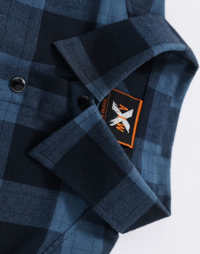 A blue and black plaid unisex flannel shirt with a collar and buttons, featuring a logo.