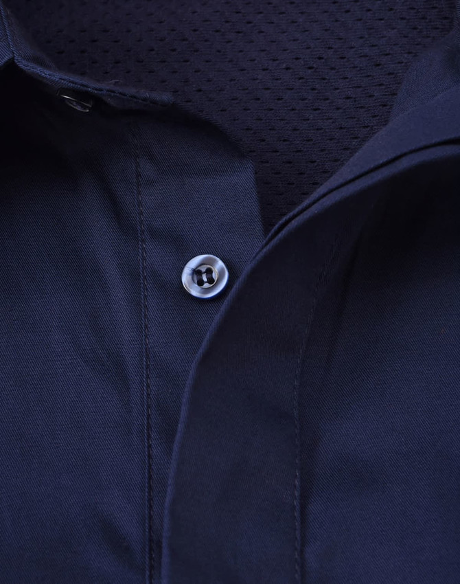 A navy blue long sleeve work shirt with a closed front and mesh interior. It features a button at the collar and has a branded logo.