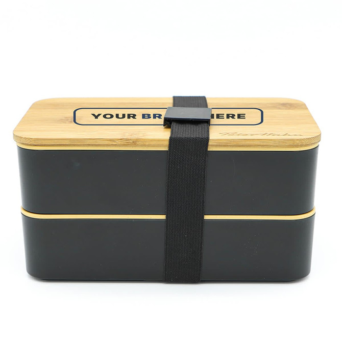 A two-layer lunch box in black and natural wood, featuring a secure strap and a branding area on the lid.