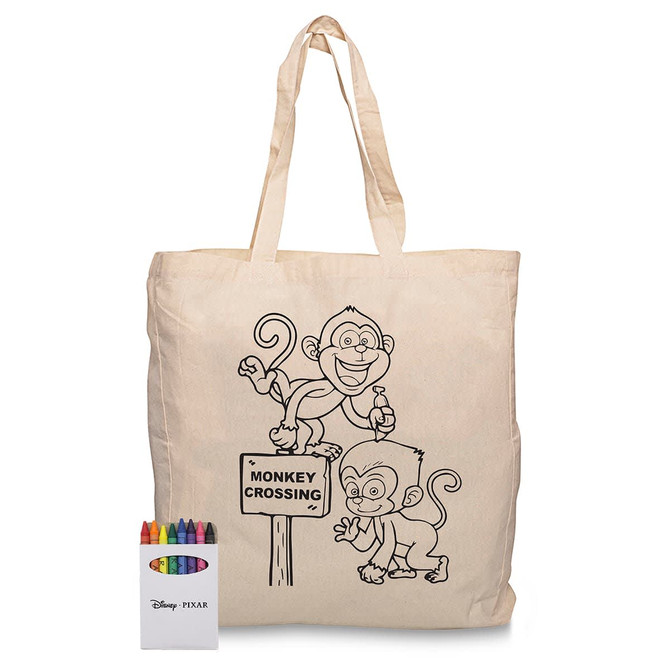 A cream-coloured calico bag featuring monkey designs and a set of crayons in various colours beside it.