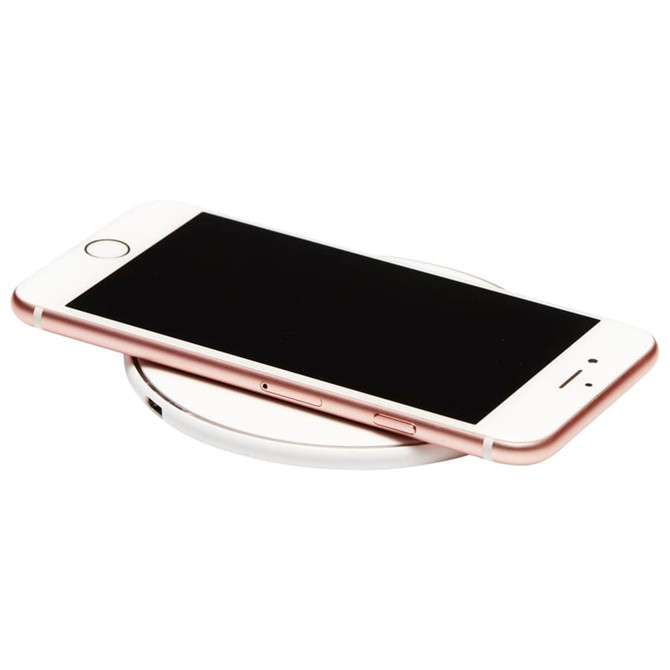 A round wireless charging dock in white, with a smartphone resting on top. The phone has a rose gold edge.