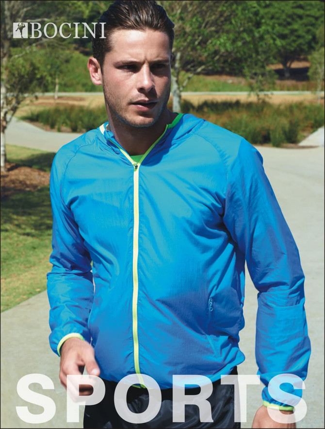A man wearing a bright blue unisex rain jacket with a yellow zipper and trim in an outdoor setting.