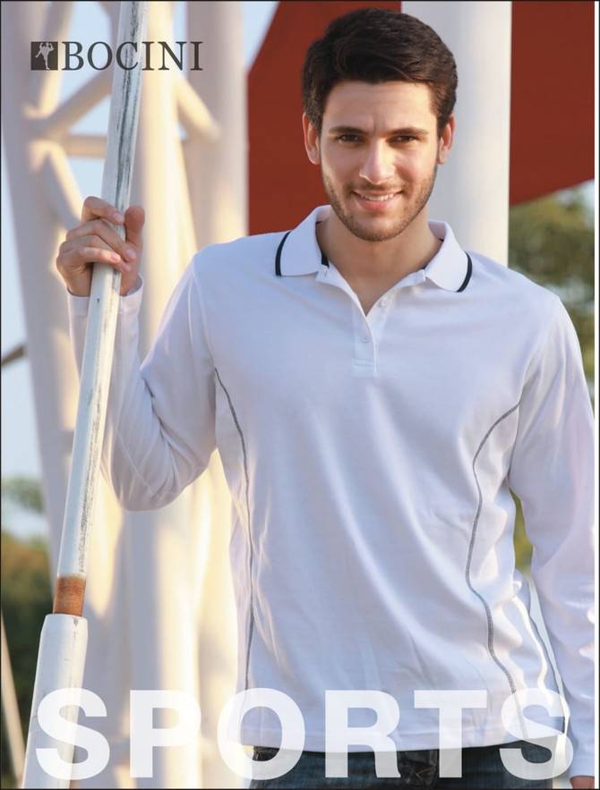A young man in a white long-sleeve polo shirt with a branded logo, standing outdoors near a pole.