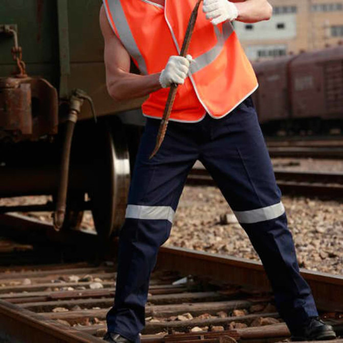 Unisex adults cotton drill work pants in navy with reflective tape, worn by a person in an orange hi-vis vest.
